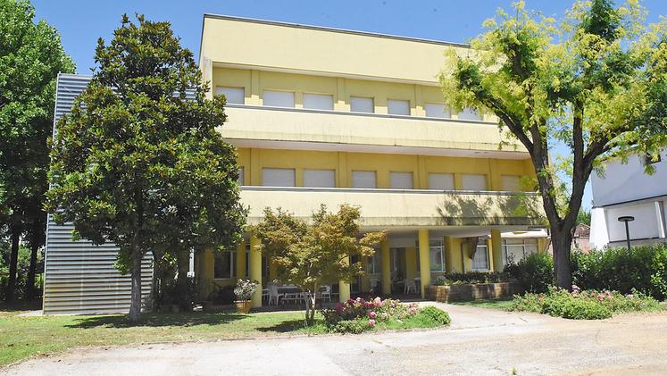 Struttura gialla a tre piani con giardino e sedie bianche Struttura gialla a tre piani con giardino e sedie bianche