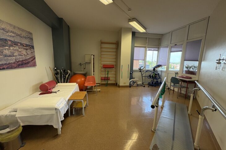 Stanza ben attrezzata per fisioterapia, con lettino, parallele e cyclette