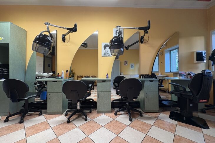 Postazioni con specchi e caschi asciugacapelli in una sala gialla ben curata