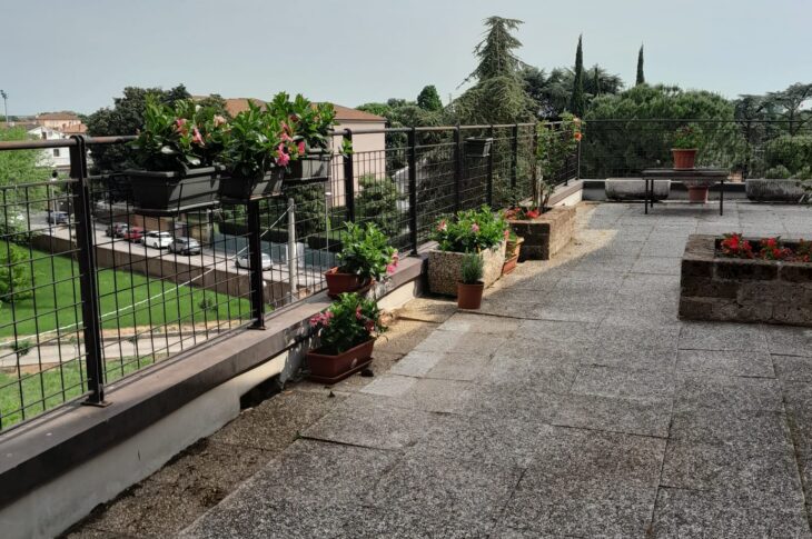 Terrazzo panoramico con piante verdi e panchine.