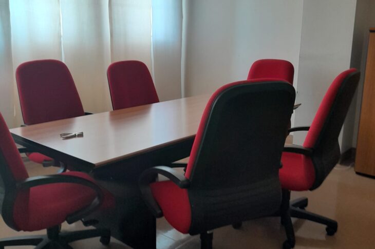 Ufficio con ampio tavolo in legno e poltrone rosse.