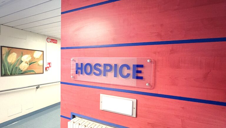 Corridoio pulito con scritta Hospice su parete rossa e quadro di tulipani Corridoio pulito con scritta Hospice su parete rossa e quadro di tulipani