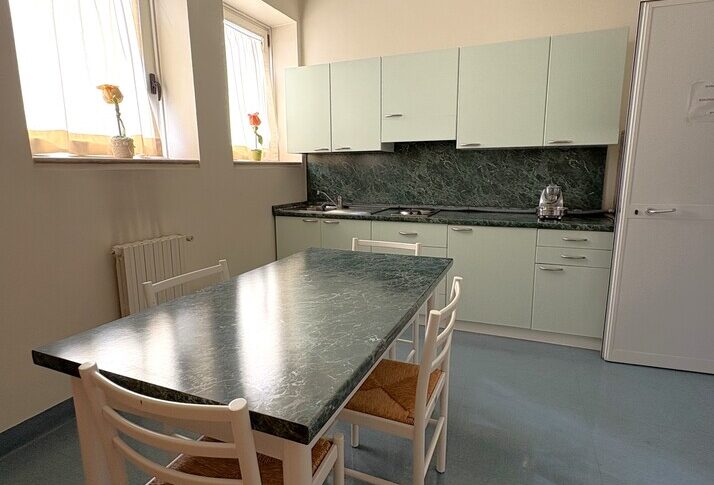 Tavolo in marmo verde con sedie bianche, mobili chiari di una cucina