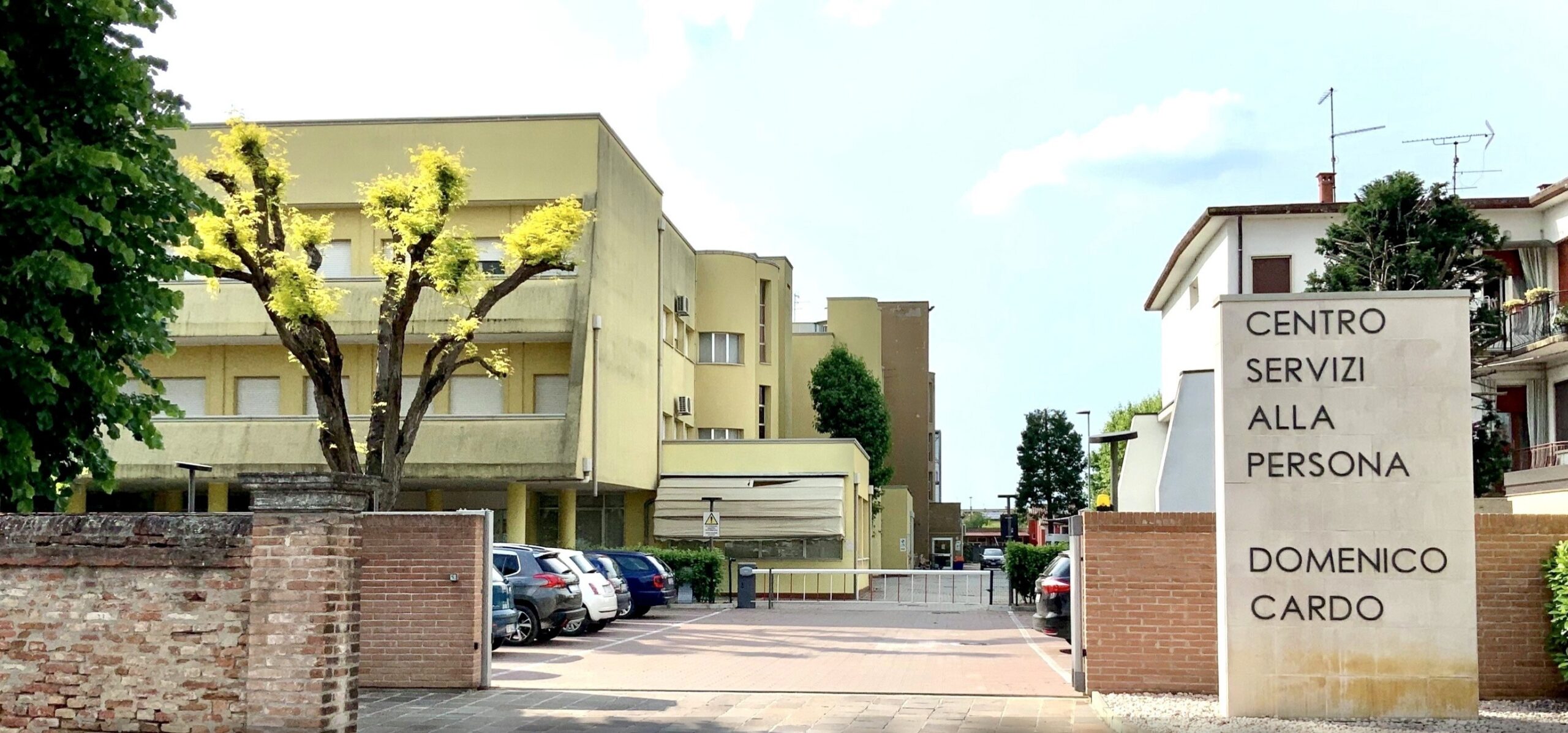 Insegna Centro Domenico Cardo accanto a edifici gialli e parcheggio alberato